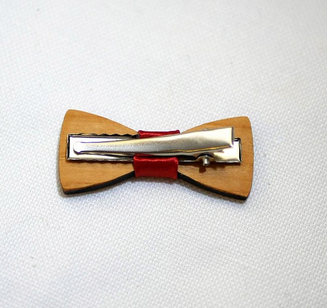Barrette en bois avec nœud papillon et ruban rouge.
