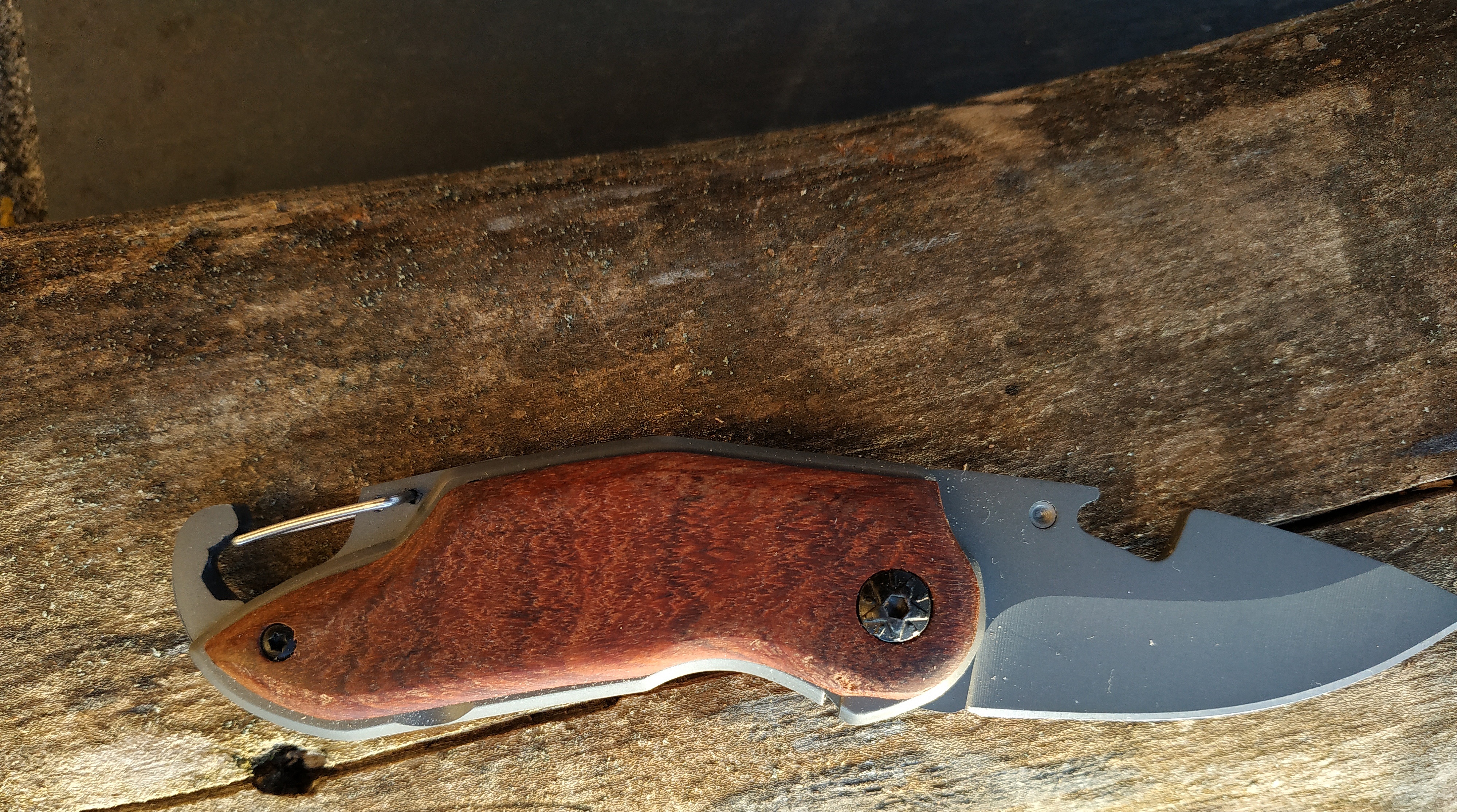 Couteau de poche pliable avec manche en bois gravé.