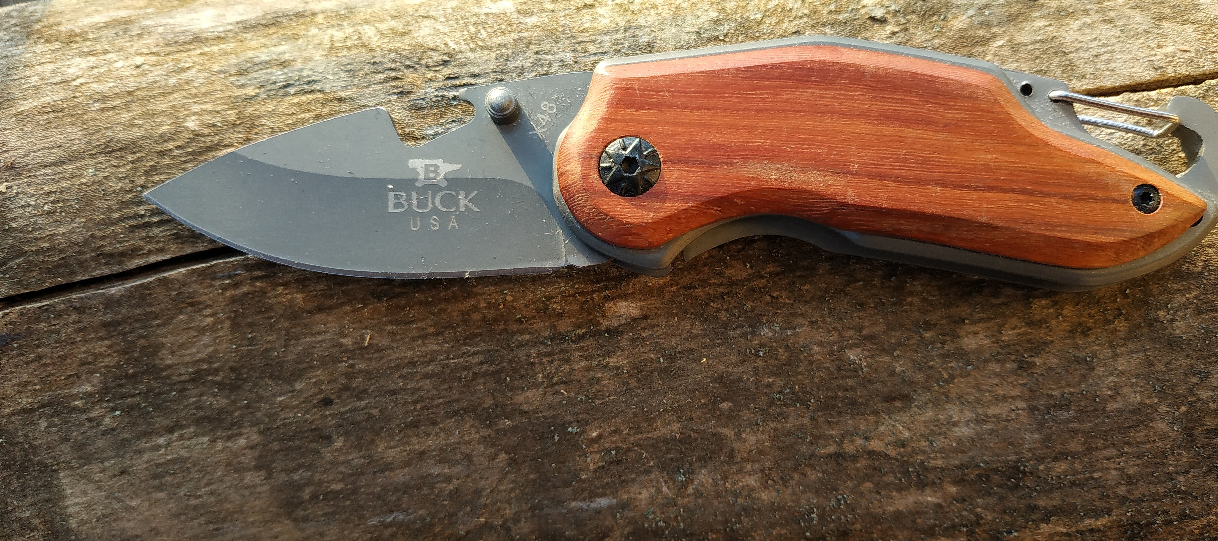 Couteau de poche pliable Buck avec manche en bois gravé.