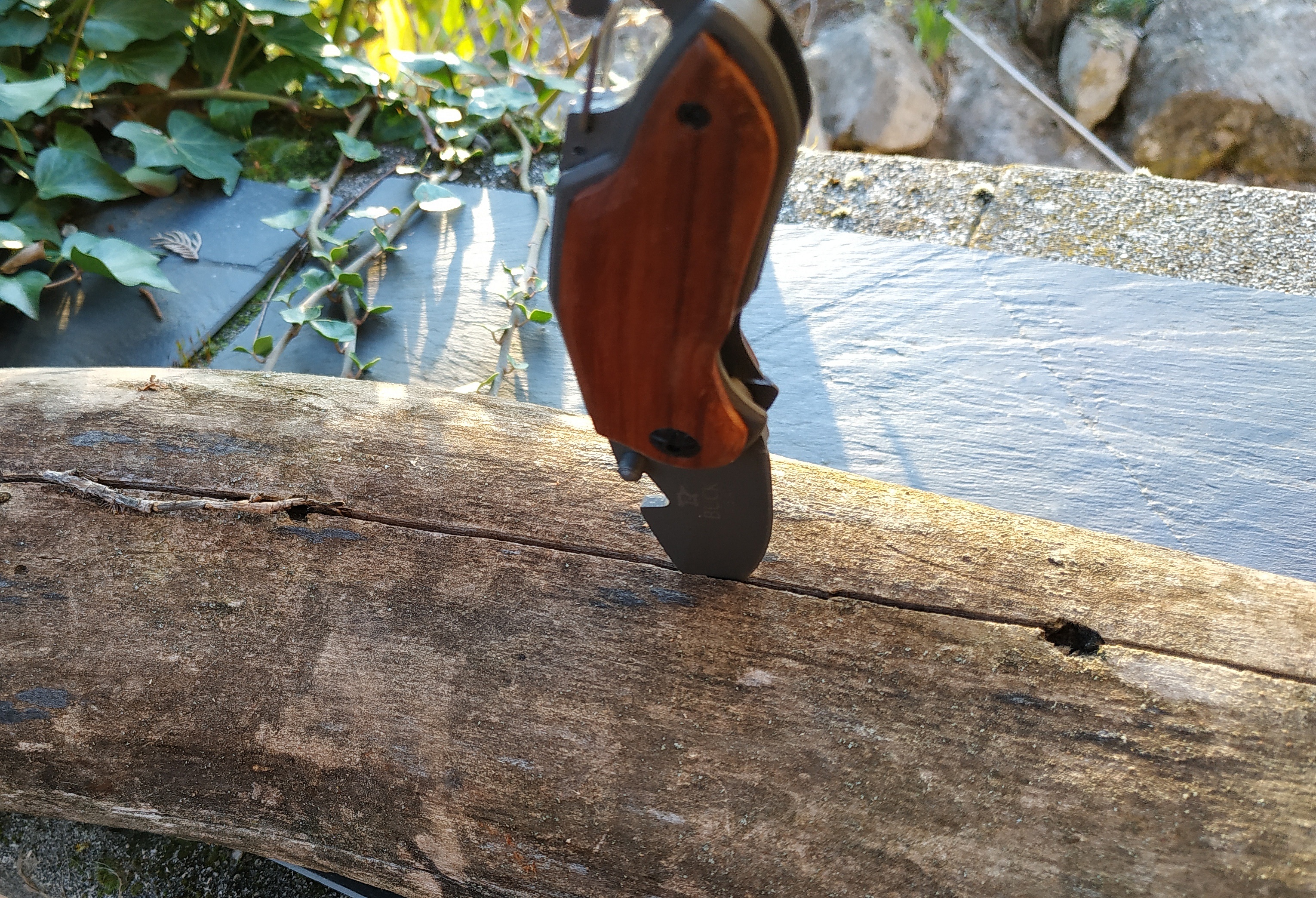 Couteau de poche pliable avec manche en bois gravé.