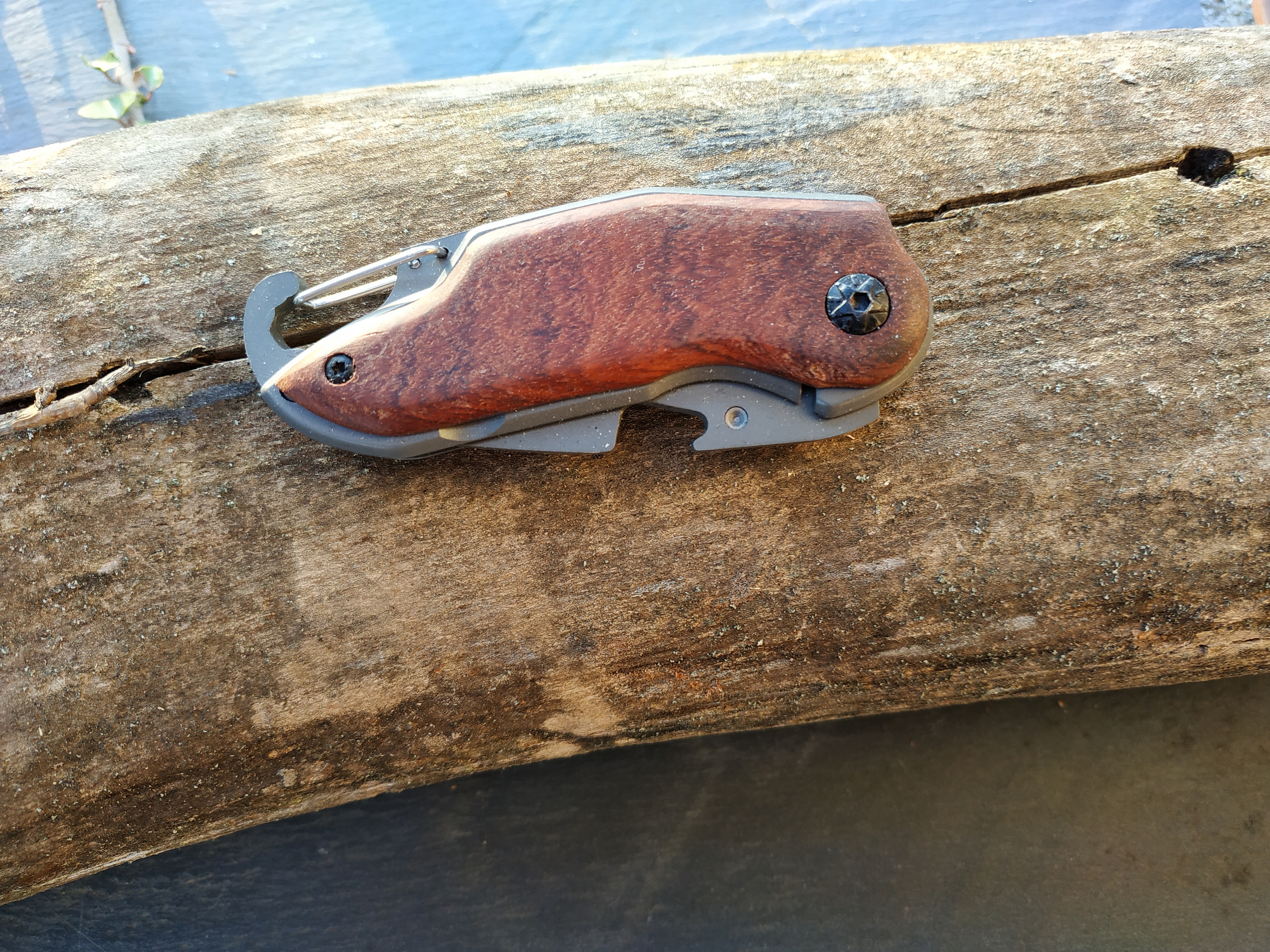 Couteau de poche pliable avec manche en bois sur bois.