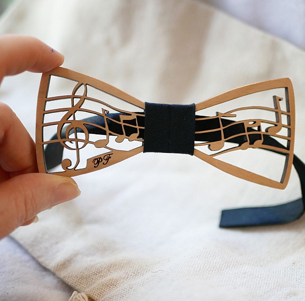 Nœud papillon en bois découpé avec motif de partition musicale.
